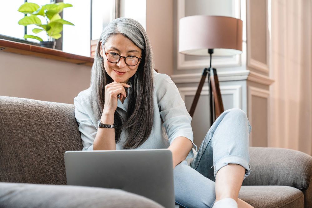 Woman looking at a screen sitting on a couch 